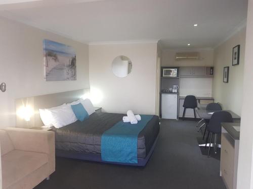 a bedroom with a bed and a couch and a kitchen at Caravilla Motor Inn in Taree