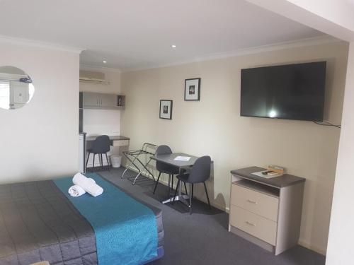 a hotel room with a bed and a flat screen tv at Caravilla Motor Inn in Taree