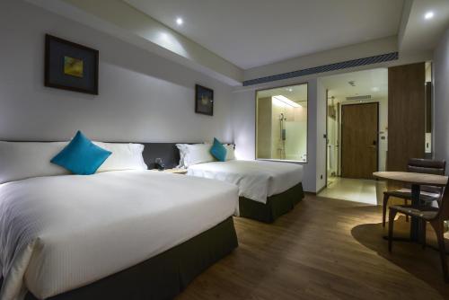 a hotel room with two beds and a table at Just Sleep Kaohsiung Station in Kaohsiung