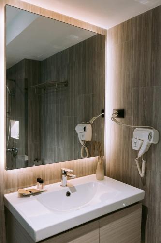 a bathroom with a white sink and a large mirror at The Rich Hotel in Nakhon Ratchasima