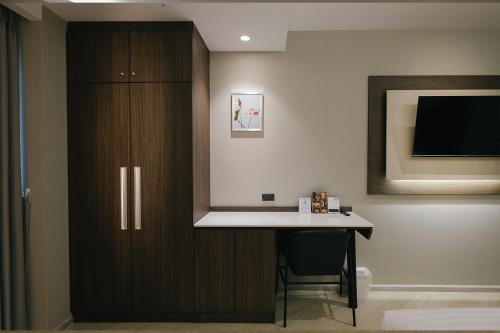 a room with a desk and a tv on a wall at The Rich Hotel in Nakhon Ratchasima