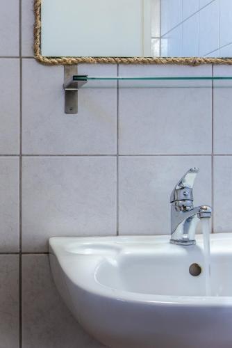 a bathroom sink with a faucet and a mirror at Kanso Rooms in Galatás