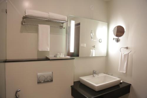 a white bathroom with a sink and a mirror at Rangalaya Royal in Vellore