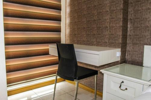 a desk with a chair next to a wall at Minimalist Studio Apartment with City View at M-Town Residence By Travelio in Tangerang