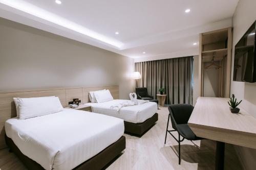 a hotel room with two beds and a desk at The Rich Hotel in Nakhon Ratchasima