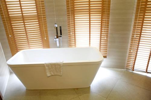 a white bath tub in a bathroom with windows at Ciao SaiGon Hotel & Spa in Ho Chi Minh City