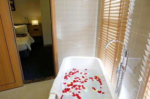 a bathroom with a bath tub filled with red flowers at Ciao SaiGon Hotel & Spa in Ho Chi Minh City