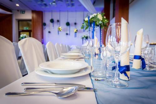a long table with plates and wine glasses on it at Qubus Hotel Gorzów Wielkopolski in Gorzów Wielkopolski