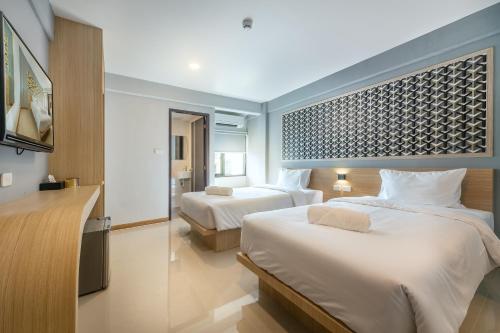 ラヨーンにあるPLAAI Play Hotelのベッド2台とテレビがあるホテルの部屋