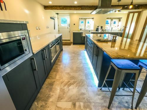 a large kitchen with blue cabinets and a counter at Luxury traditional stone farmhouse in Saddleworth in Oldham