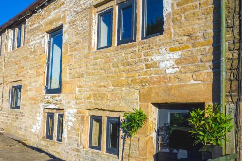 a brick building with windows and plants on it at Luxury traditional stone farmhouse in Saddleworth in Oldham