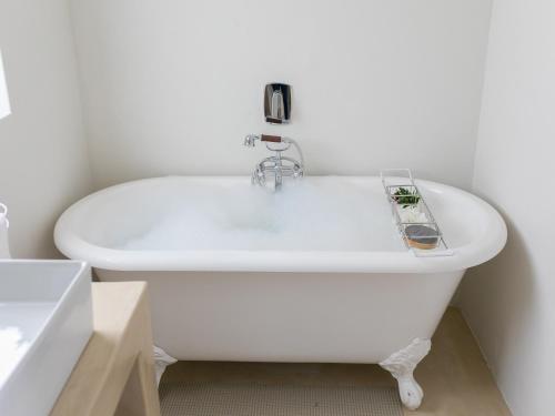 a white bath tub in a bathroom with a sink at 401 Rozendal Cottages in Stellenbosch