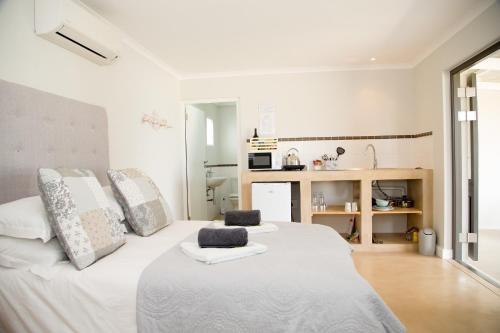 a bedroom with a large white bed with two pillows at 401 Rozendal Cottages in Stellenbosch