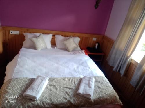 a bedroom with a white bed with two towels on it at Rufina Lachung de'CROWN in Lachung