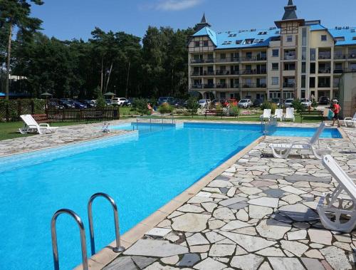 a large swimming pool with a hotel in the background at Blue Mare Perfect in Łukęcin
