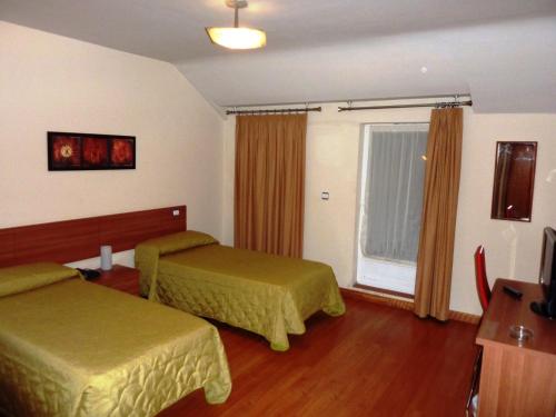 a hotel room with two beds and a window at Hostal La Morada in La Cistérniga