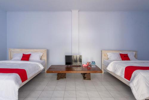 Cette chambre comprend 2 lits et une table. dans l'établissement RedDoorz Syariah @ Bondowoso City Center, à Bondowoso