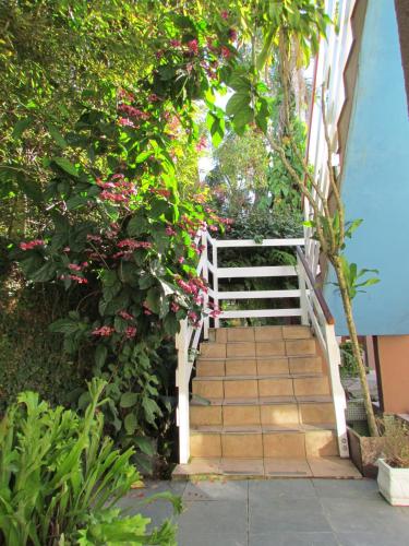 a stairway with a white railing and flowers at Pousada Vila da Praia in Bertioga