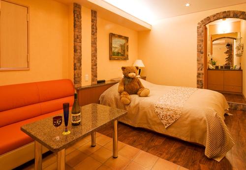 a teddy bear sitting on a bed in a room at Hotel TO in Wakayama