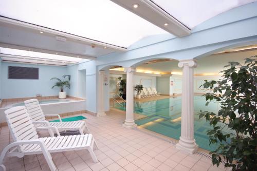 a swimming pool with two white chairs and a swimming pool at Imperial Hotel in Llandudno