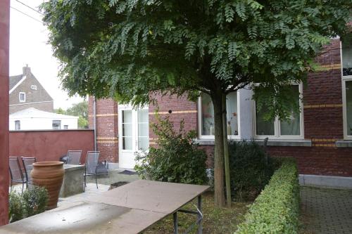 a picnic table under a tree in front of a house at De Oude School 4 pers app in Visé