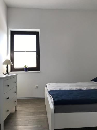a bedroom with a bed and a dresser and a window at Ferienwohnung II in Papenburg