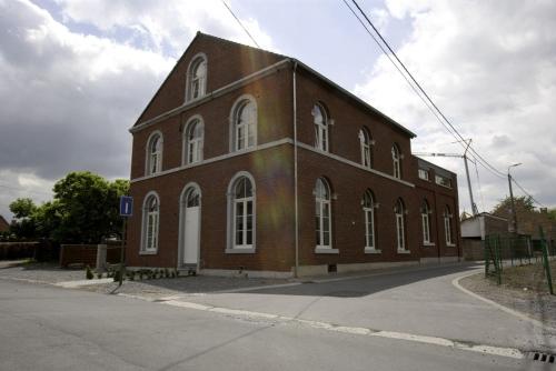 a large brick building with white windows on a street at De Oude School in Visé