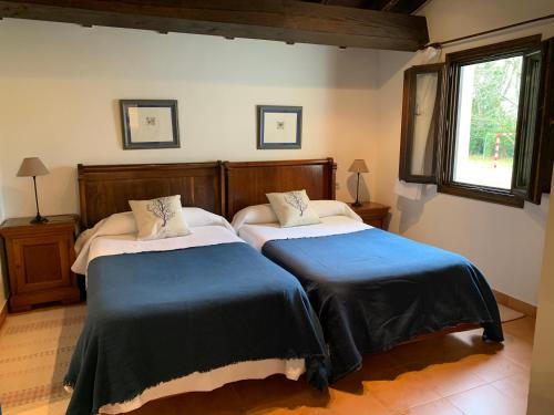 1 dormitorio con 2 camas y ventana en Apartamentos Buga, en Posada