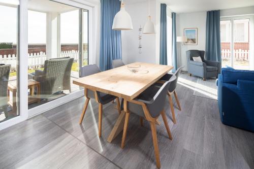 ein Esszimmer mit einem Holztisch und Stühlen in der Unterkunft Deichsonne - mit Wintergarten und Blick Richtung Wattenmeer in Juist