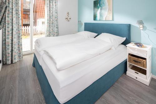 Schlafzimmer mit einem Bett mit blauem Kopfteil in der Unterkunft Deichsonne - mit Wintergarten und Blick Richtung Wattenmeer in Juist