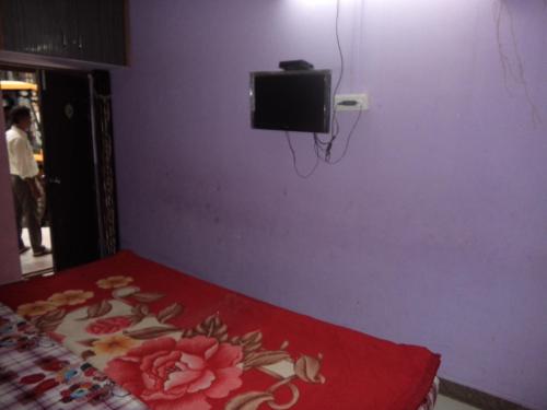 a bedroom with a bed and a tv on a purple wall at Parwati in Nainital