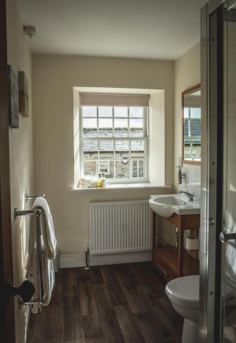a bathroom with a sink and a toilet and a window at The Saddle Room in Middleham