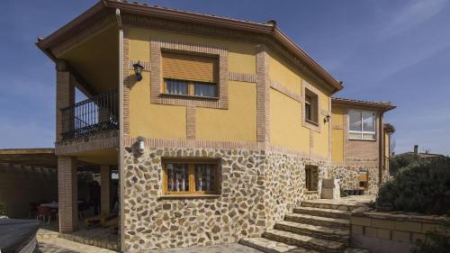 una casa amarilla con una pared de piedra y escaleras en Flor de la Jara, en Cobisa