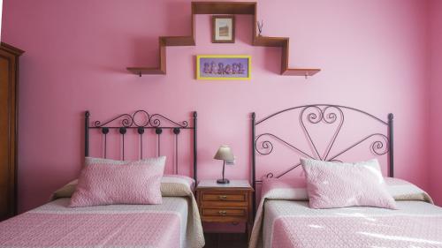 two beds in a room with pink walls at Flor de la Jara in Cobisa