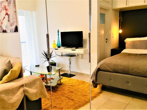a bedroom with a bed and a television and a table at Cozy Studio by seaside and tram in Athens