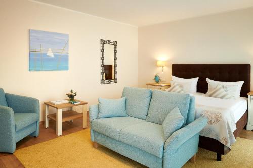 a bedroom with a bed and two blue chairs at Hotel Nautilus in Putbus