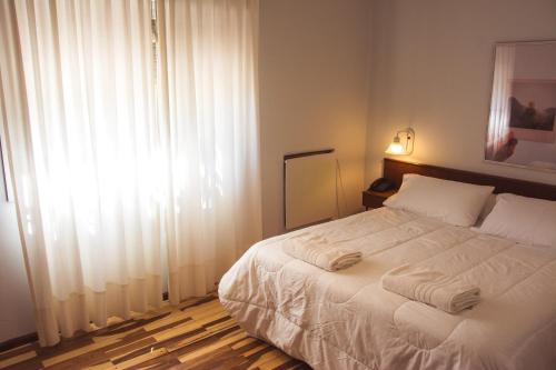 a bedroom with a bed with white sheets and a window at Solares Hotel & Spa in Alta Gracia