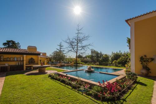 a backyard with a swimming pool with flowers and a house at Quinta das Pedras in Sintra