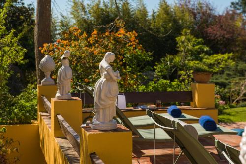 a group of statues sitting on tables in a garden at Quinta das Pedras in Sintra