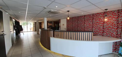 a lobby with a counter and a red wall at Kyriad Aix Les Milles - Plan de Campagne in Bouc-Bel-Air