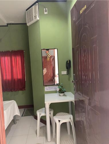 a bathroom with a table and two stools and a mirror at First Baby Bytes Guest House in Siquijor