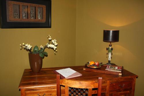 a desk with a lamp and a vase of flowers on it at Art Hotel Neckar in Neckargemünd