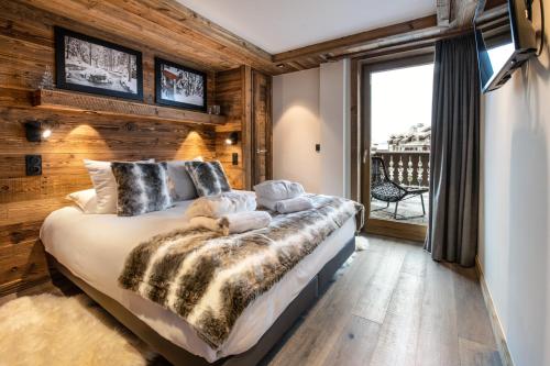 a bedroom with a large bed with a wooden wall at Manali Lodge by Alpine Resorts in Courchevel