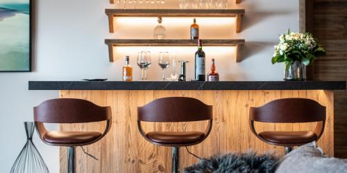 a bar with three chairs and wine glasses at Manali Lodge by Alpine Resorts in Courchevel