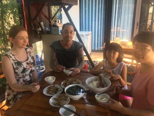 a group of people sitting around a table eating food at Bebe Homestay Phu Quoc in Phu Quoc