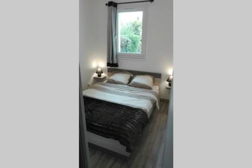 une chambre avec un lit et une fenêtre dans l'établissement Appartement jardin a 100m de la plage et Thalasso, à Concarneau