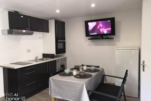 Il comprend une cuisine avec une table et une télévision murale. dans l'établissement Appartement jardin a 100m de la plage et Thalasso, à Concarneau
