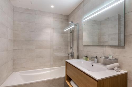 a bathroom with a tub and a sink and a bath tubermottermott at Manali Lodge by Alpine Resorts in Courchevel