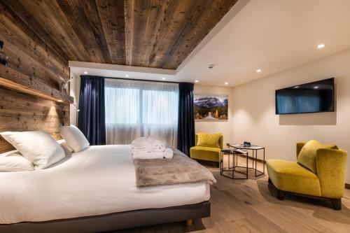 a hotel room with a large bed and two chairs at Manali Lodge by Alpine Resorts in Courchevel