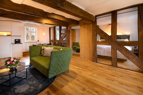 a living room with a green couch and a bed at Hotel Brunnenhaus Schloss Landau in Bad Arolsen